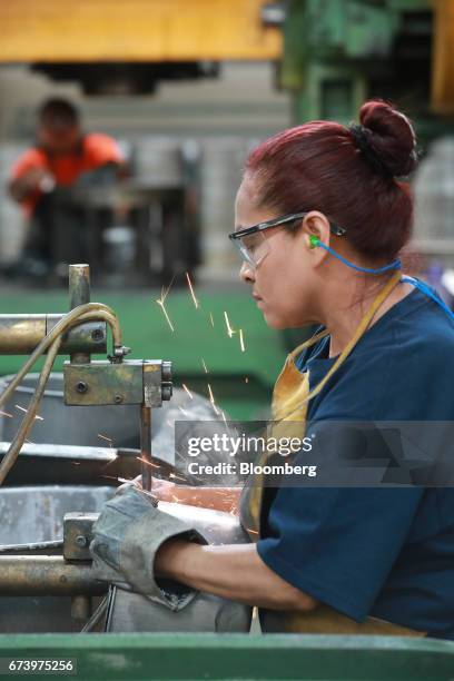 An employee uses a machine to attach a handle onto a pewter pot at the Baro Industrial SA manufacturing facility in the Azcapotzalco neighborhood of...