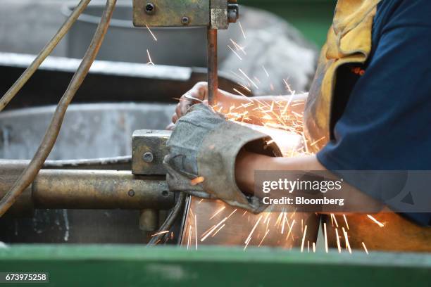 An employee uses a machine to attach a handle onto a pewter pot at the Baro Industrial SA manufacturing facility in the Azcapotzalco neighborhood of...