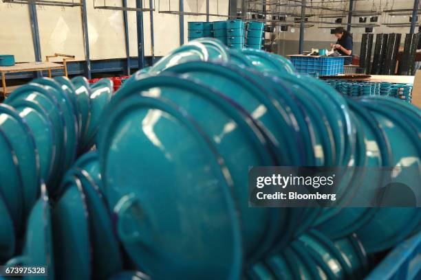 An employee works as enameled pewter cookware sits in piles at the Baro Industrial SA manufacturing facility in the Azcapotzalco neighborhood of...