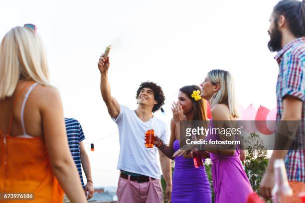 young friends having fun with smoke bombs at the rooftop party - grounds stock pictures, royalty-free photos & images