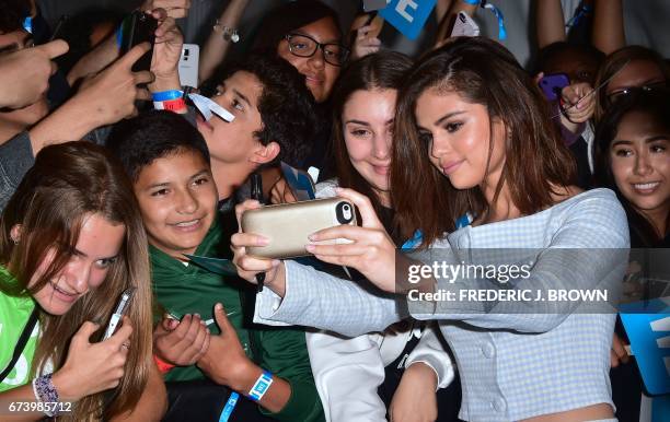 Selena Gomez takes pictures with her fans on her carpet arrival at We Day 2017 in Inglewood, California on April 27, 2017.