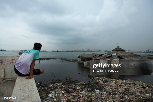 An Indonesian youth looks out to sea next near an abandoned mosque which was overtaken by the sea on April 26, 2017 in Jakarta, Indonesia. Jakarta,...