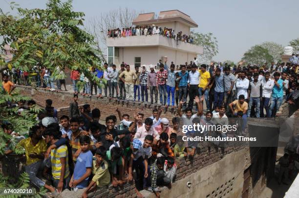 People stand on the roof and trees for seeing the leopard in Durga colony of Sohna, on April 27, 2017 some 25 km from Gurgaon, India.