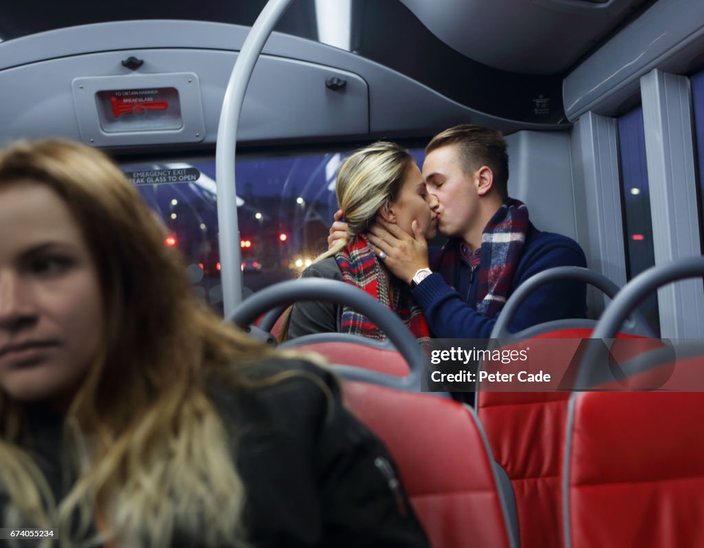 Young couple kissing at back of bus