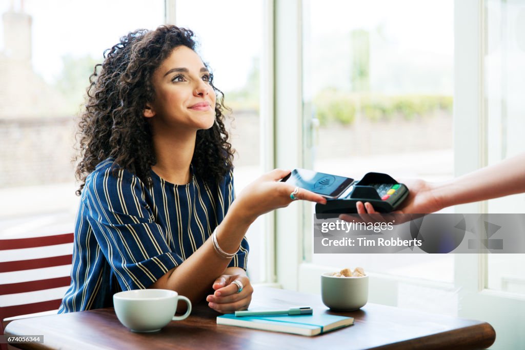 Woman using mobile payment in coffee shop