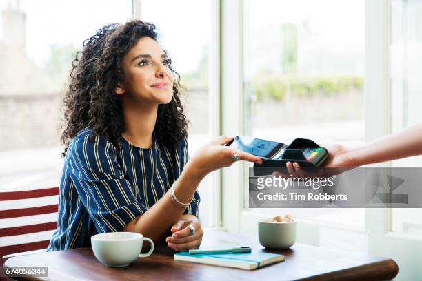 woman using mobile payment in coffee shop - paying stock-fotos und bilder
