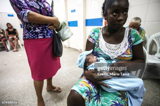 Young patient Davi Luca is held by his mother Liliane Soares da Silva as they wait to see Dr. Êcaro Vidal dos Santos at the Posto Saude Santa Monica...