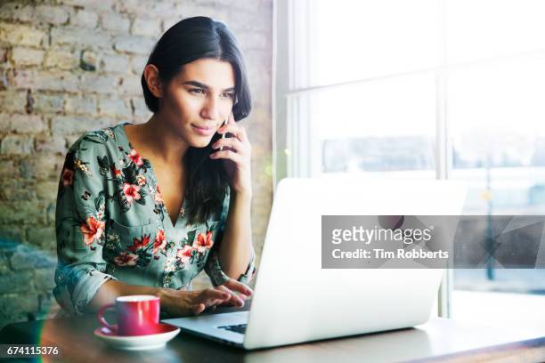 woman using smartphone and laptop in coffee shop - busy coffee shop stock pictures, royalty-free photos & images