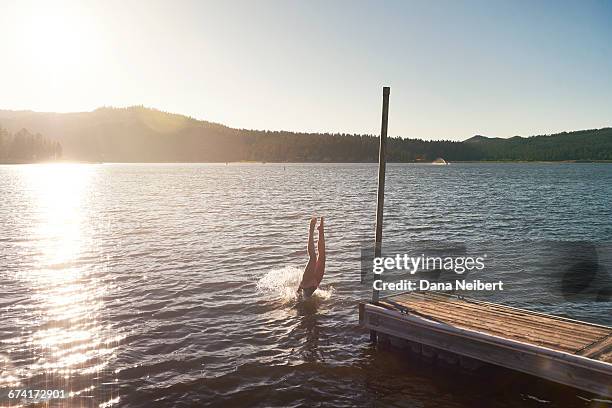 girl dives into lake from dock. - big bear lake stock pictures, royalty-free photos & images