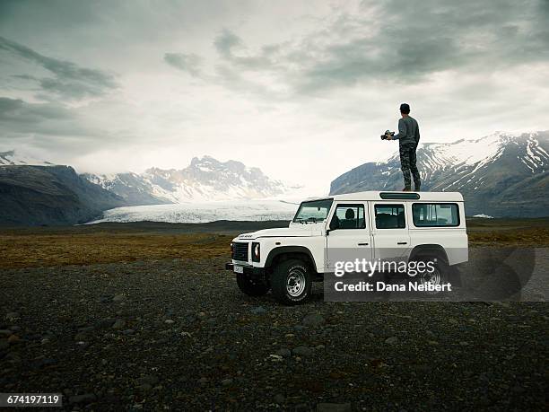 man taking pictures on top an off-road vehicle. - iceland mountains stock pictures, royalty-free photos & images