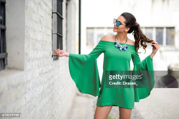 attractive young woman wearing vibrant green silk dress - womenswear stock pictures, royalty-free photos & images