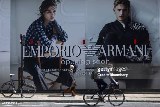 Cyclist and a pedestrian pass an advertising hoarding for a new Emporio Armani store, operated by Giorgio Armani SpA, on Bond Street in London, U.K.,...
