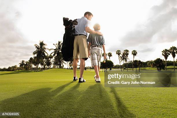 father and son playing golf in early morning light - rijk stockfoto's en -beelden