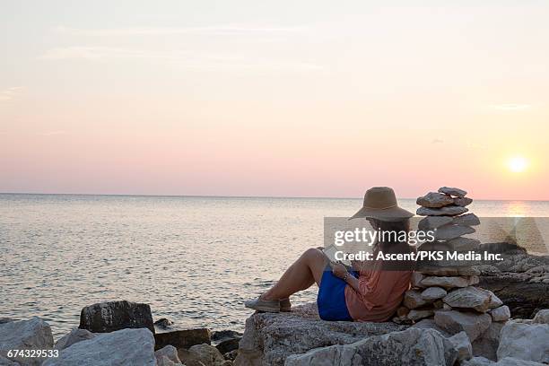 woman relaxes, uses digital tablet, sea behind - stack of sun lounges stock pictures, royalty-free photos & images