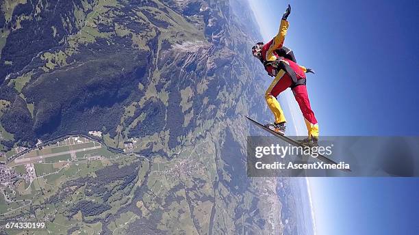 skydiver in freefall, on snowboard over mtns - skydiving stock pictures, royalty-free photos & images