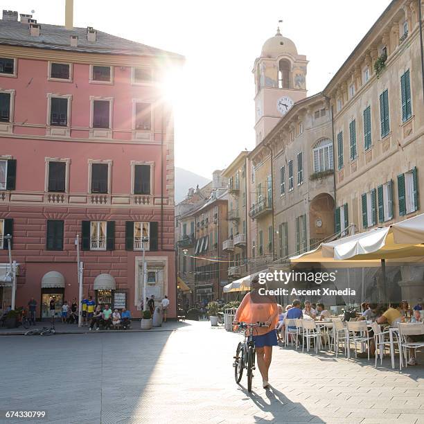 woman pushes bike through town piazza, sunrise - italian cafe culture stock pictures, royalty-free photos & images