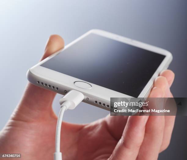 Detail of a hand holding an Apple iPhone 7 with a Silver finish and a headphone jack adaptor, taken on September 23, 2016.
