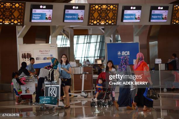 Passengers walk past check-in counters at Terminal 3 of the Soekarno-Hatta airport in Tangerang, on the outskirts of Jakarta on April 28, 2017....