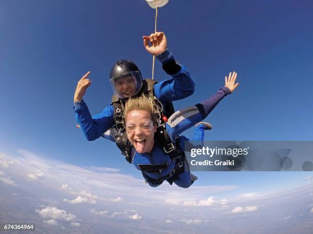 skydiving tandem showing the tongue - adrenalina fotografías e imágenes de stock