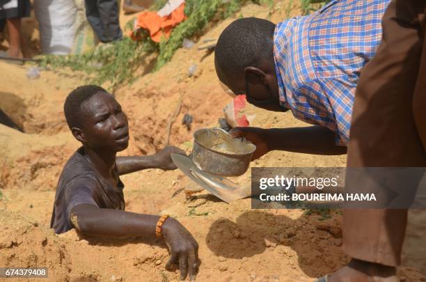 Man looks at a bowl near a digger searching gold on April 25, 2017 in Kafa-Koira, south of Niamey. Hundreds of people, sometimes whole families, rush...