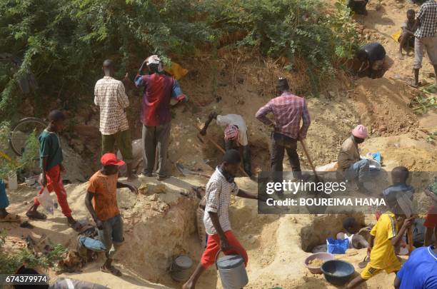 People dig in the soil as hundreds of people search gold on April 25, 2017 in Kafa-Koira, south of Niamey. Hundreds of people, sometimes whole...