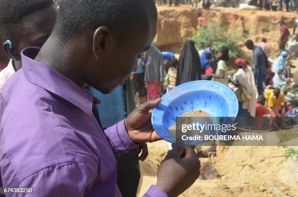 Man looks in a sieve as hundreds of people search gold on April 25, 2017 in Kafa-Koira, south of Niamey. Hundreds of people, sometimes whole...