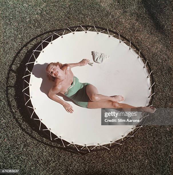 American swimmer and actress Esther Williams lounging on a trampoline, circa 1956.