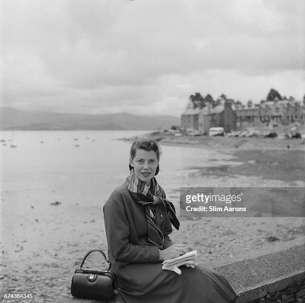 Rita Aarons, wife of photographer Slim Aarons, poses on a beach in Wales, 1957.