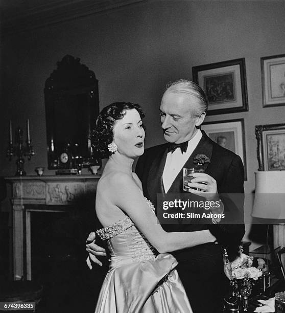 English photographer Cecil Beaton and Mrs. Julien Chaqueneau at Kitty Miller's New Year's Eve party on Park Avenue, New York City, 1952.