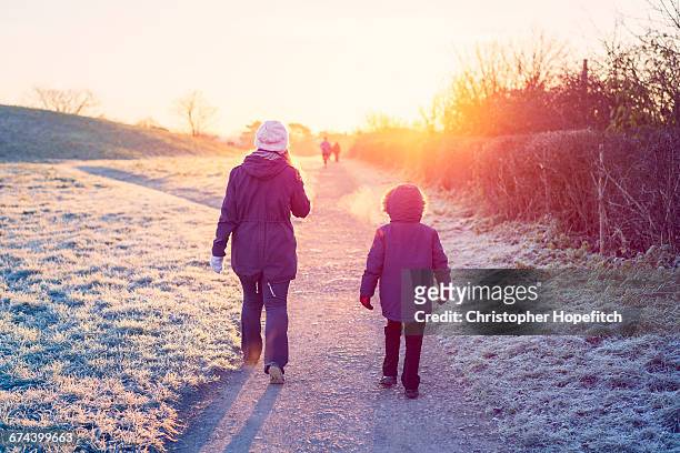 mother and son walking through a park in winter - winter stock pictures, royalty-free photos & images