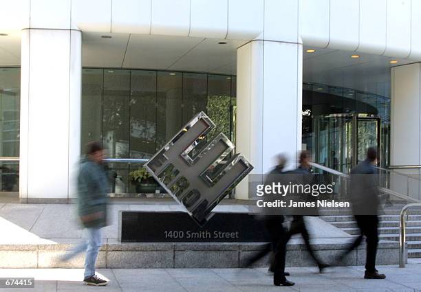 Employees of the Houston-based energy trading firm Enron walk past the company's logo outside the corporate headquarters November 29, 2001 in...