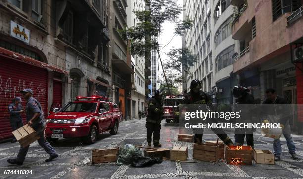 Firefighters put out debris set on fire during a general strike against the Brazilian social welfare reform project in Sao Paulo, Brazil, on April...