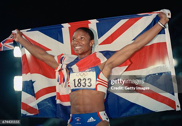 Draped in the Union flag, Denise Lewis of Great Britain celebrates winning the gold medal for the Women's Heptathlon event during the XXVII Olympic...