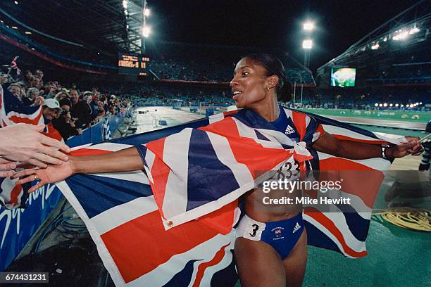 Draped in the Union flag, Denise Lewis of Great Britain celebrates winning the gold medal for the Women's Heptathlon event during the XXVII Olympic...