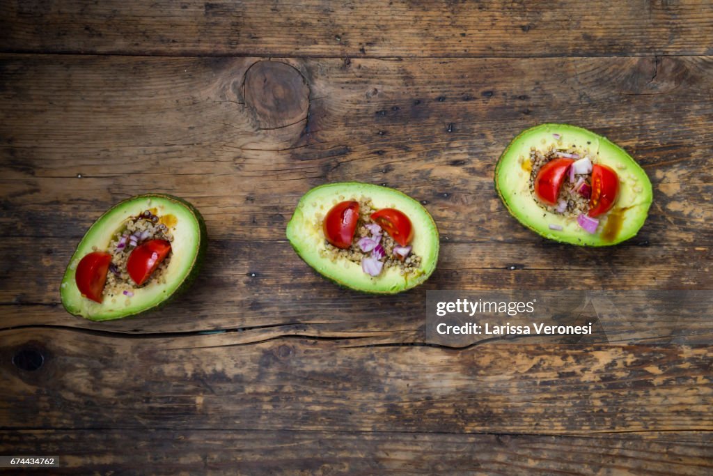 Sliced avocado filled with quinoa, cherry tomatoes and red onion