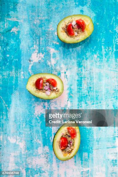 sliced avocado filled with quinoa, cherry tomatoes and red onion - larissa veronesi bildbanksfoton och bilder