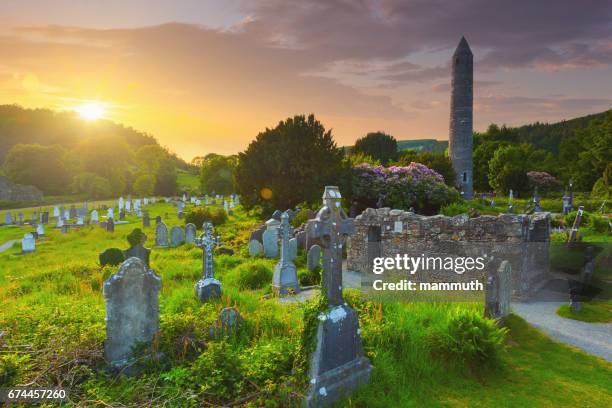 the round tower and the cemetery at the glendalough monastic site in country wicklow, ireland - irish round tower stock pictures, royalty-free photos & images