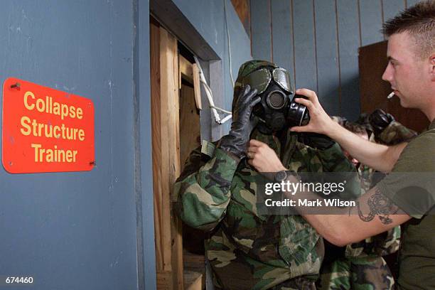 After completing a collapsed building simulation, a US Marine gets a hand with his gear during a training exercise on chemical and biological...