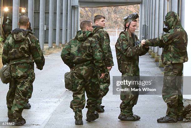 Marine gets a hand with his gear before entering a collapsed building simulator during a training exercise on chemical and biological response...