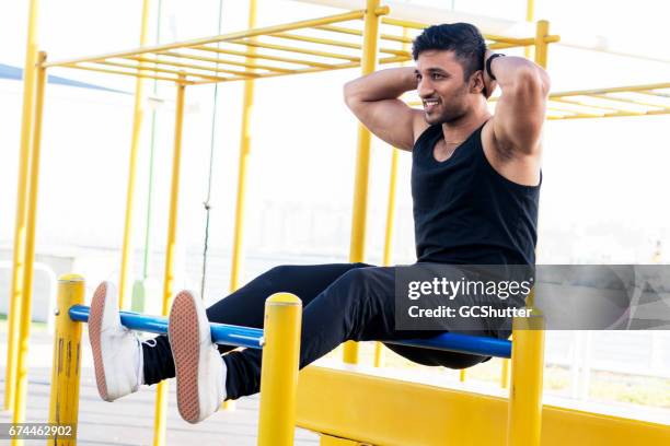 homme musclé à une salle de gym en plein air faisant situps sur les barres - asian six pack photos et images de collection