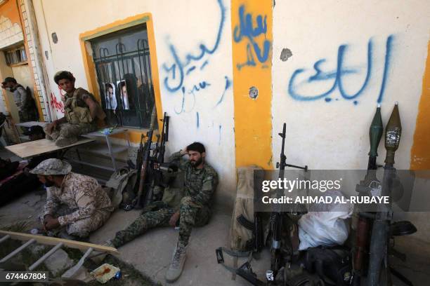 Members of the Iraqi pro-government Hashed al-Shaabi paramilitary forces rest on the side of a road in the modern town of Hatra, near the eponymous...