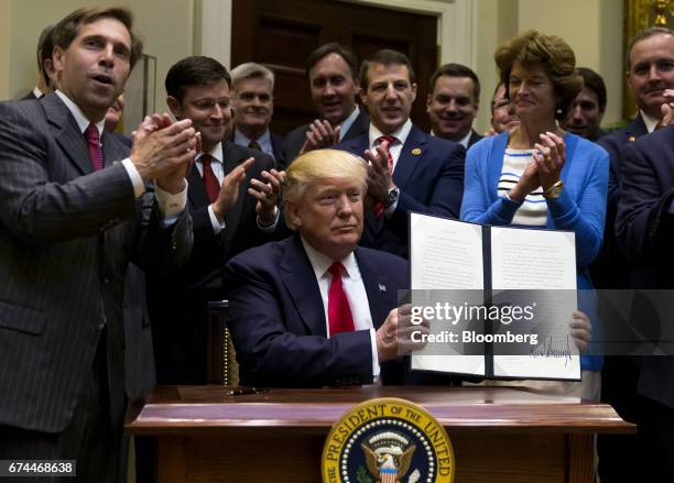 President Donald Trump holds up a signed executive order on implementing an America-first offshore energy strategy in the Roosevelt Room of the White...