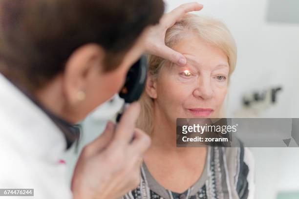 opticien op zoek naar patiënten ogen - oogmeetkunde stockfoto's en -beelden