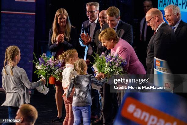 German Chancellor and Chairwoman of the German Christian Democrats Angela Merkel receives flowers as she's on stage with local CDU lead candidate...