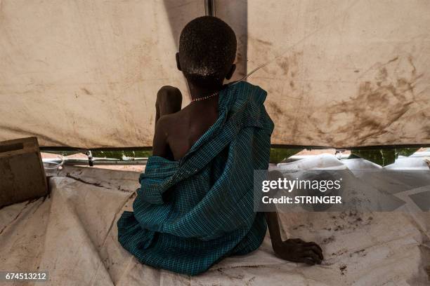 Dinka boy, suffering from cholera and severe malnutrition sits on the floor of a tent converted into a temporary field hospital near the remote...
