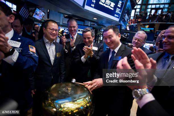 Zhengyu Wang, founder and chief executive officer of China Rapid Finance Ltd., center right, rings a ceremonial bell during the company's initial...