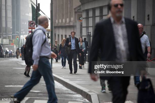 Pedestrians walk along Wall Street near the New York Stock Exchange in New York, U.S., on Friday, April 28, 2017. U.S. Stocks remained near record...