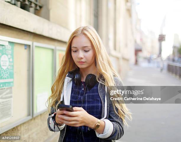 a teenage girl looking at her cell phone - blonde fille photos et images de collection