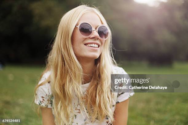 a blond young woman in a park - gafas de sol fotografías e imágenes de stock