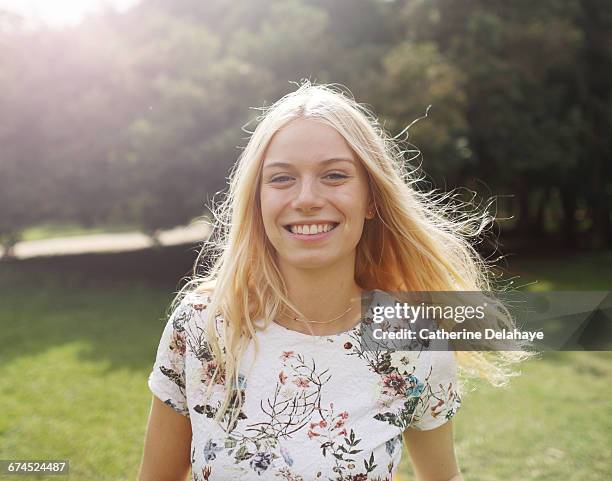 a blond young woman in a park - braune augen stock-fotos und bilder